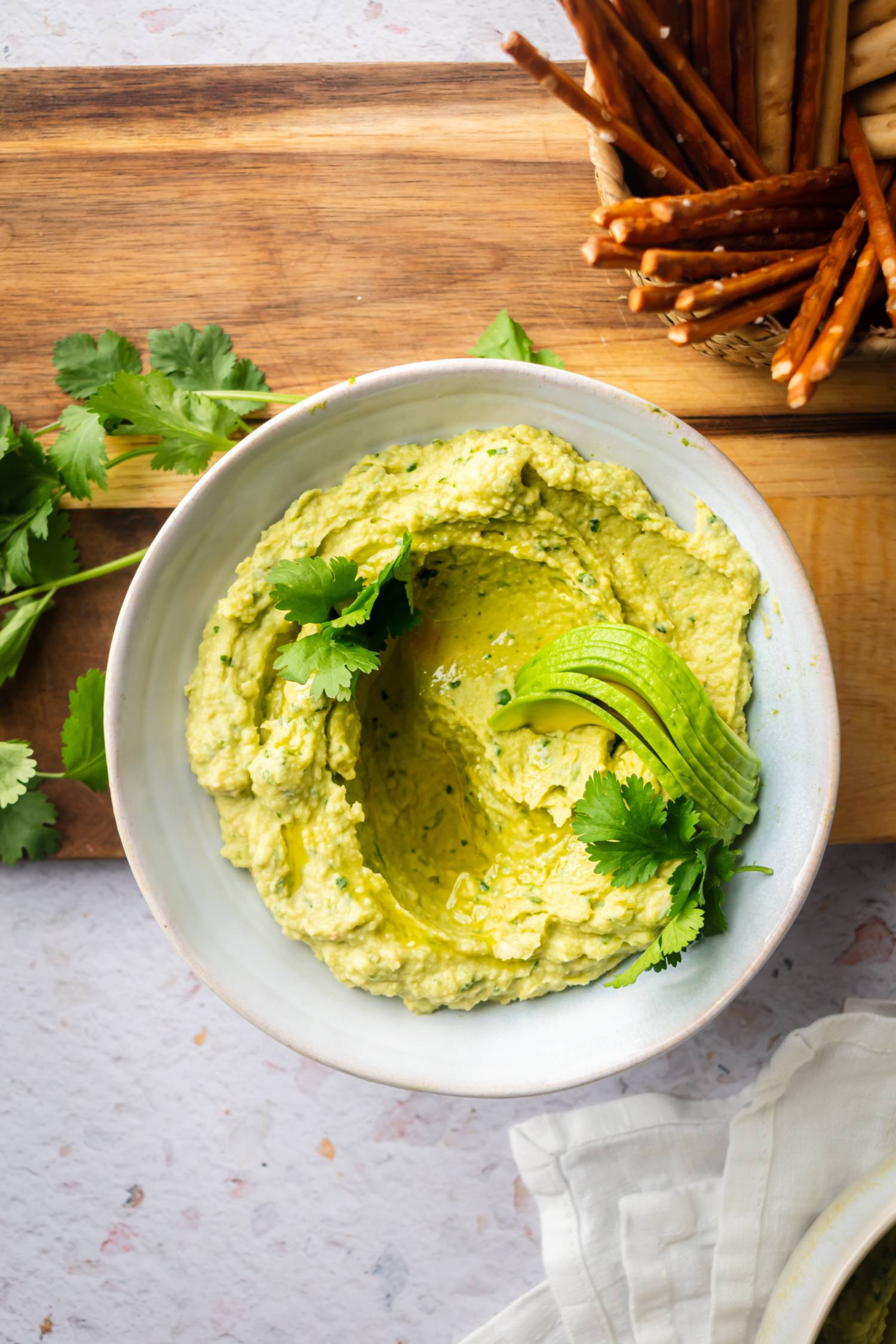 Hummus with avocado and cilantro in a bowl with fresh cilantro. 