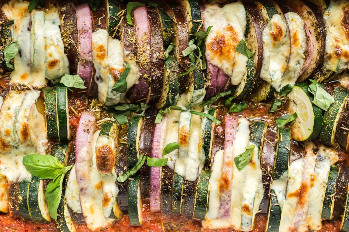 Zoomed in picture of baked ratatouille with sliced zucchini, eggplant, and summer squash covered with tomatoes, herbs, and cheese.