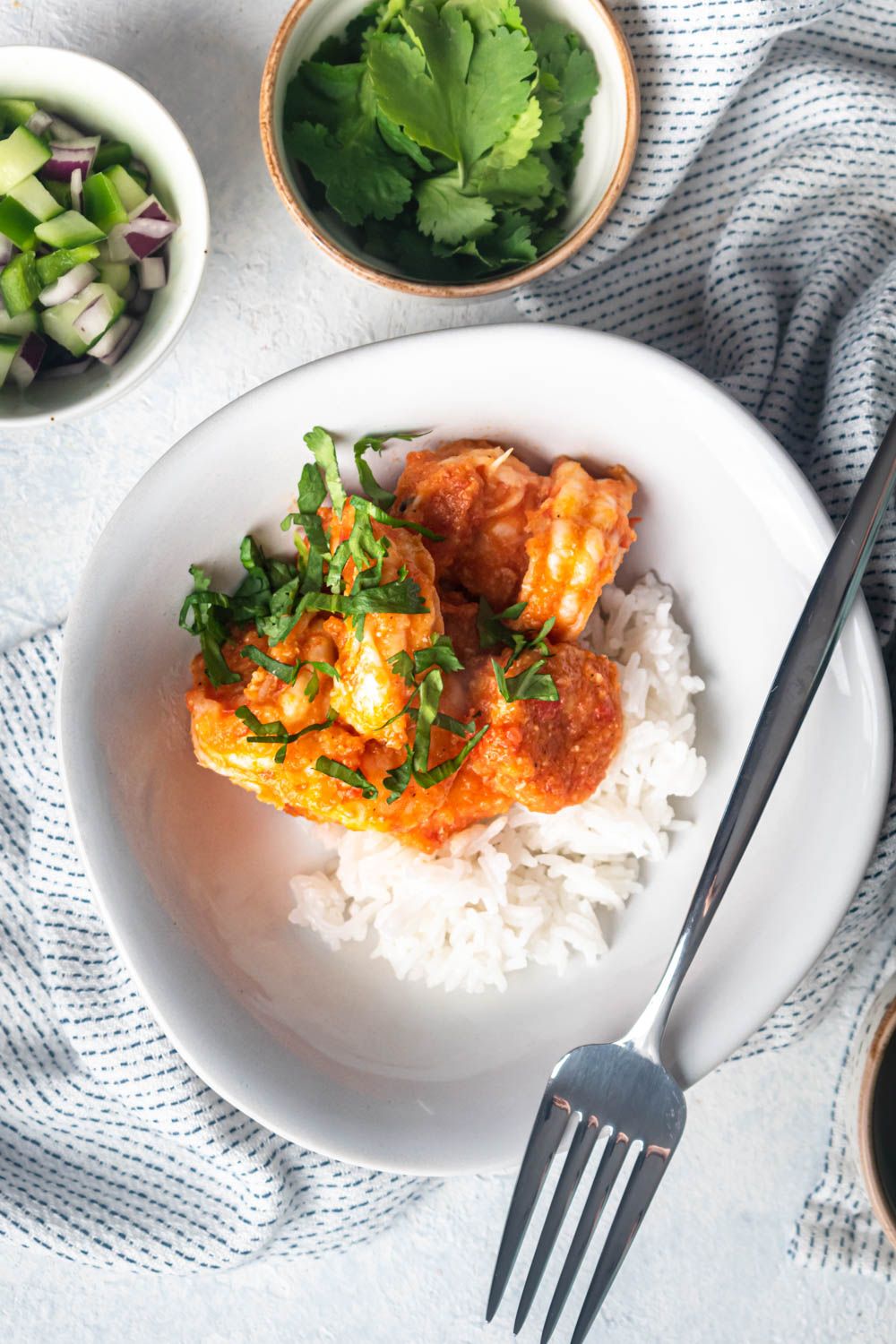 Mexican shrimp in a spicy chile sauce served in a bowl with rice and cilantro.