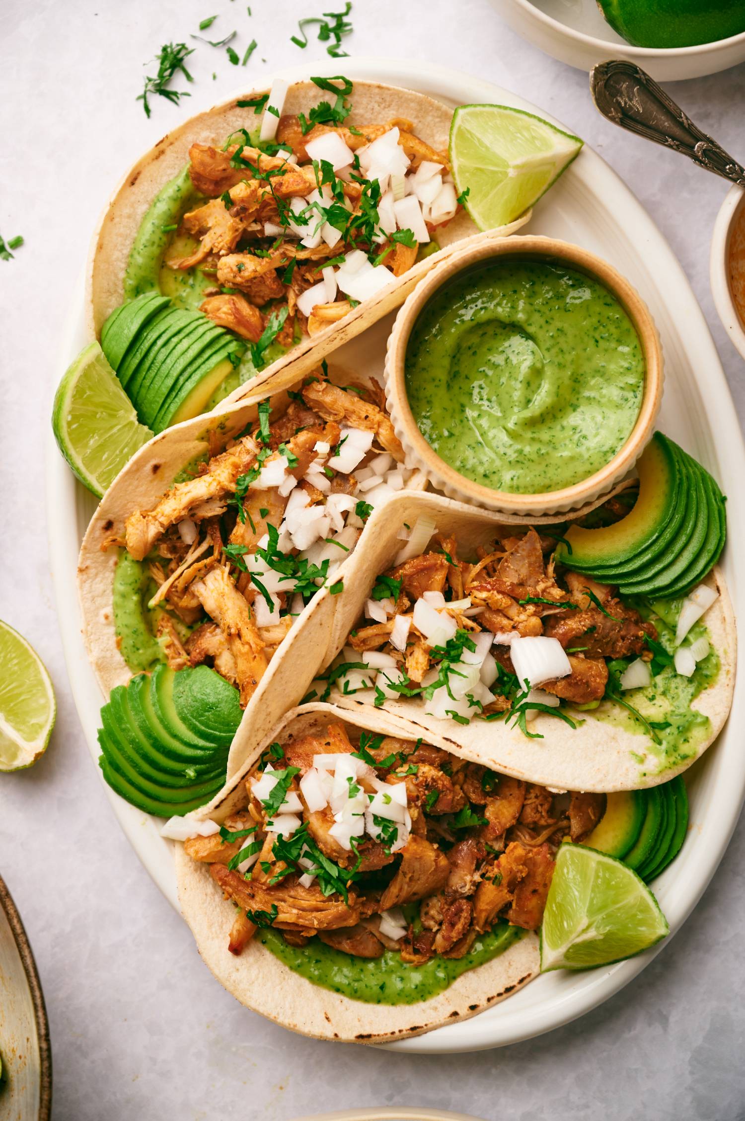 Chicken tacos with shredded chicken carnitas served in corn tortillas with avocado, cilantro, and onion.