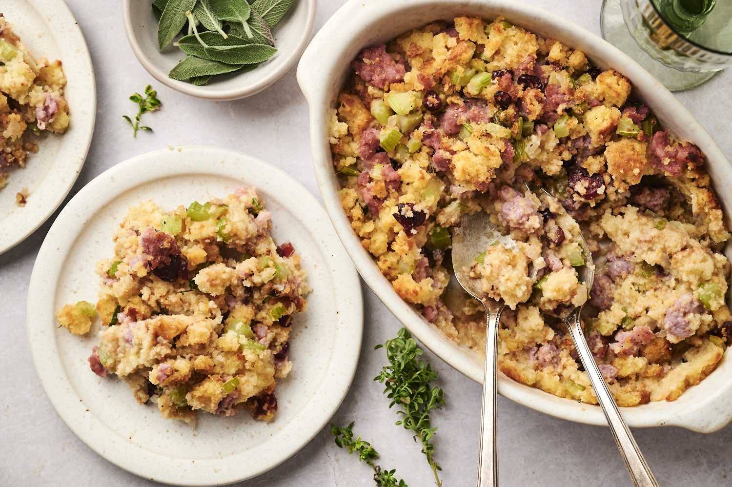Cornbread sausage stuffing being served with spoons onto a smaller plate.