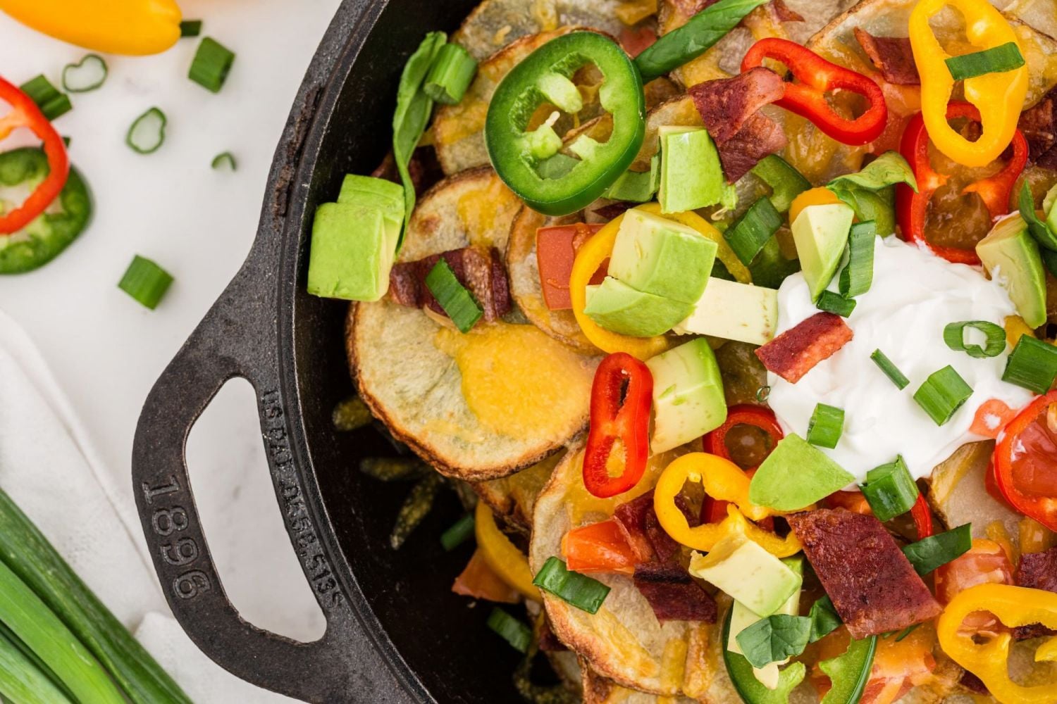 Baked potato Irish Nachos topped with bacon, green onions, jalapenos, sour cream, and avocado.