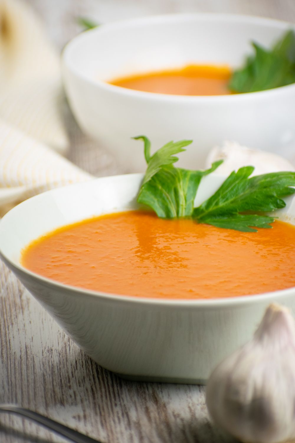 Crockpot tomato soup with chipotle peppers in a bowl with cilantro and garlic.