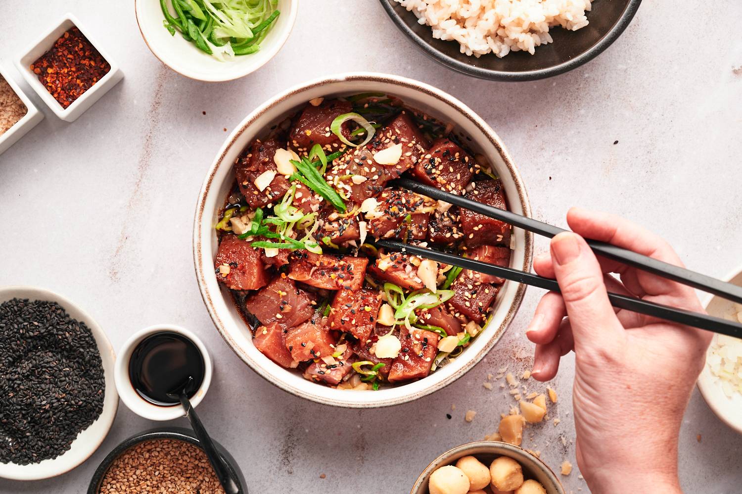 Hawaiian tuna poke in a bowl with green onions, sweet onions, soy sauce, and chopsticks.