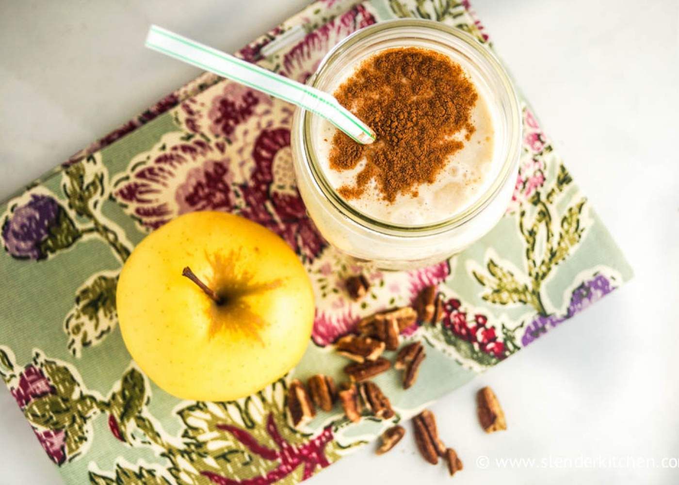 Apple smoothie in a large mason jar with apple slices on the side.