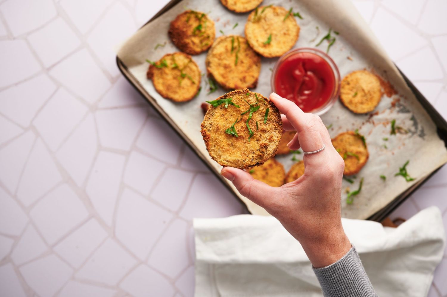 Crispy baked eggplant with breadcrumsb and herbs being picked up.