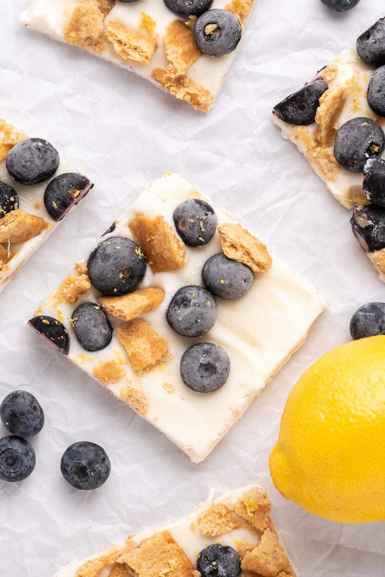 Yogurt bark pieces that are frozen and topped with blueberries and graham crackers.