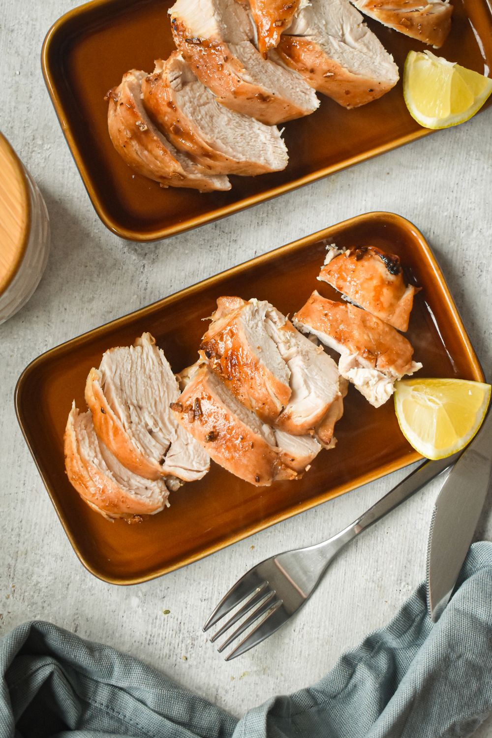 Brown sugar chicken with garlic in two brown dishes with a blue napkin.