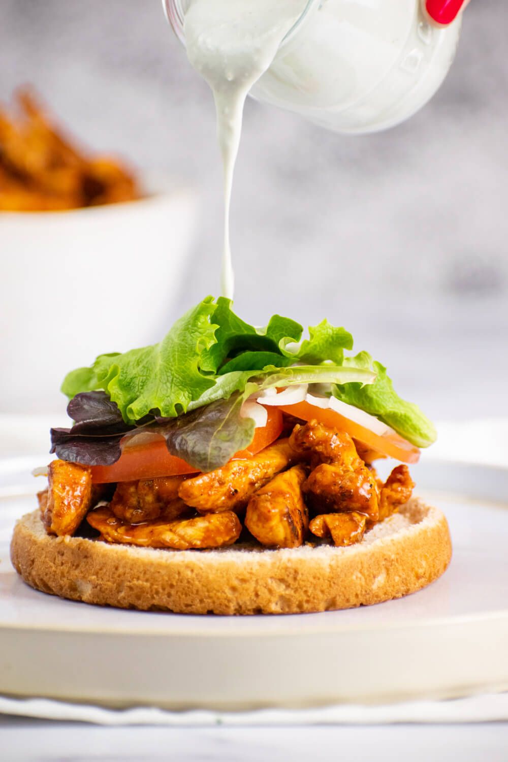 Grilled buffalo chicken sandwiches with blue cheese dressing being poured on top.