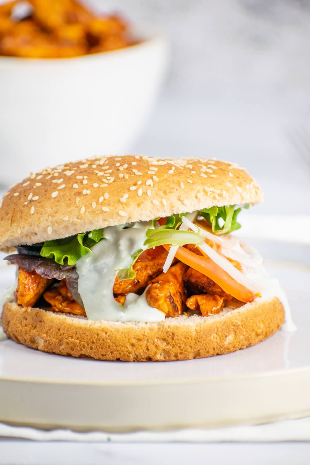 Buffalo chicken on a sandwich roll with lettuce and tomato.
