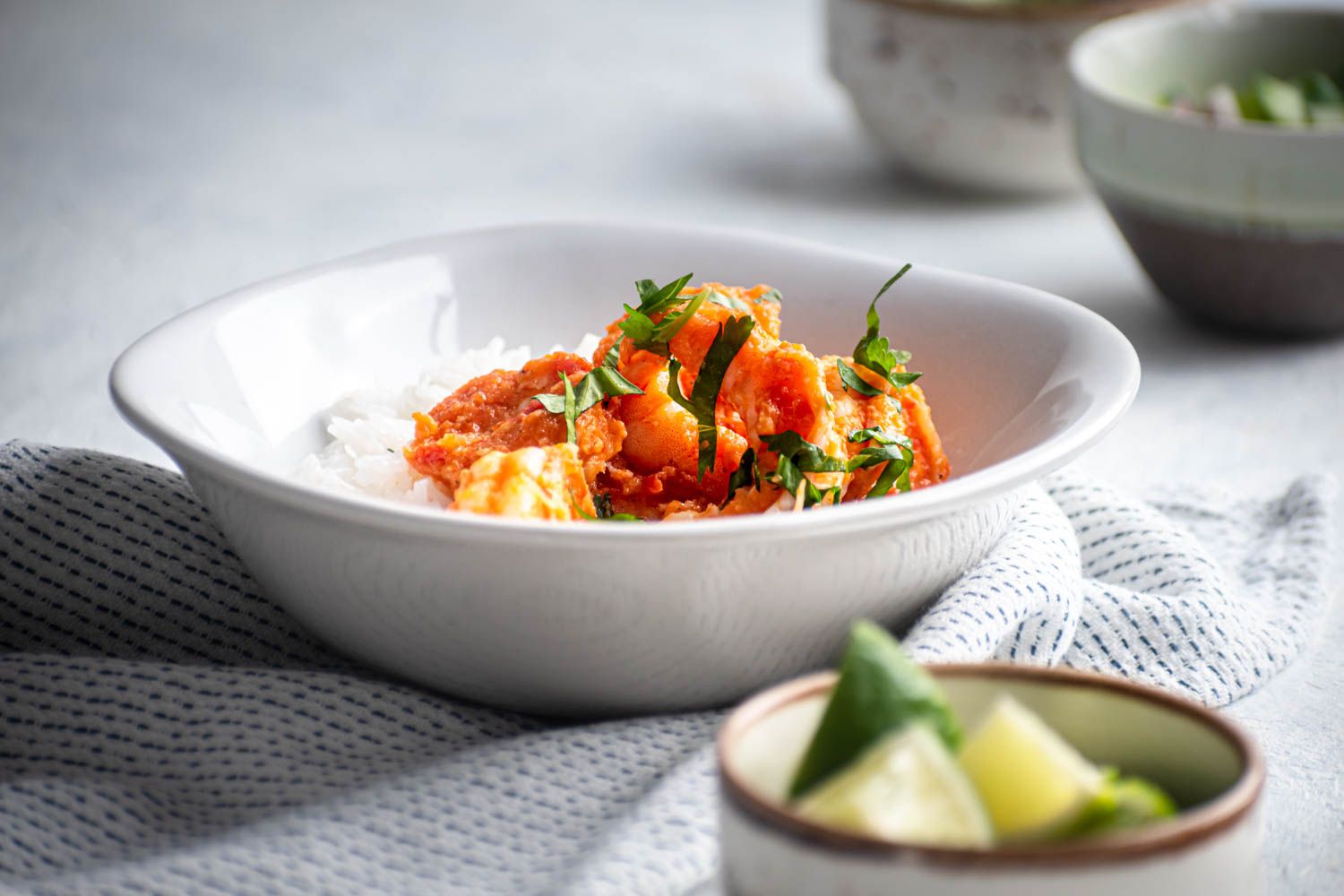 Spicy deviled shrimp in a bowl served with fresh cilantro, white rice, and lime juice.