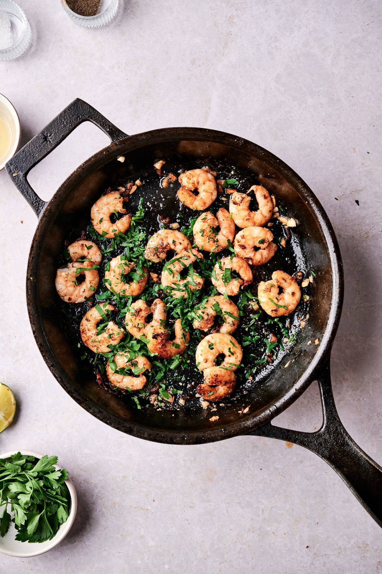 Spicy garlic shrimp in a cast iron skillet with parsley and lime juice.