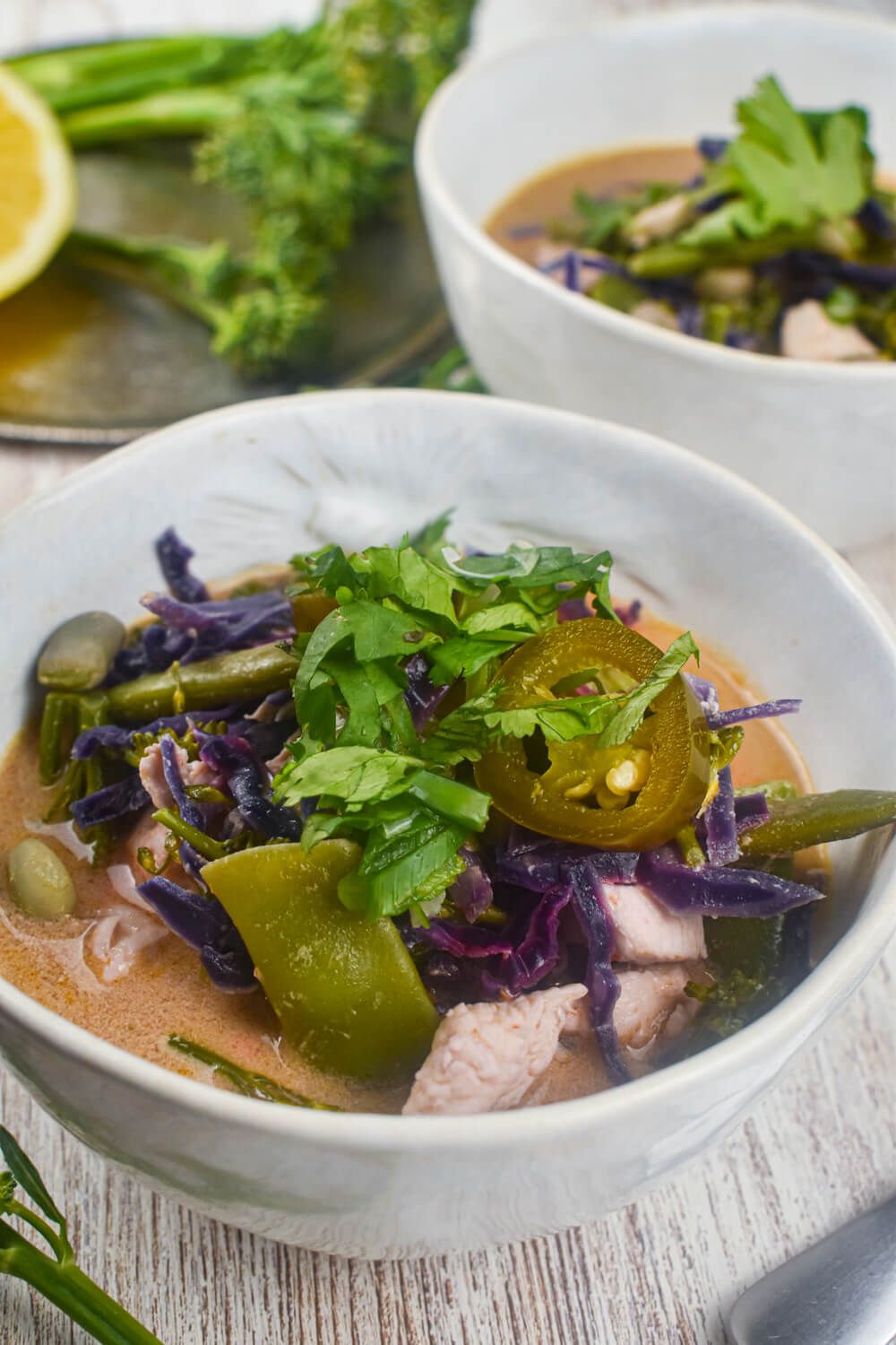 Chicken curry soup with coconut broth and vegetables in a bowl with jalapenos and cilantro.