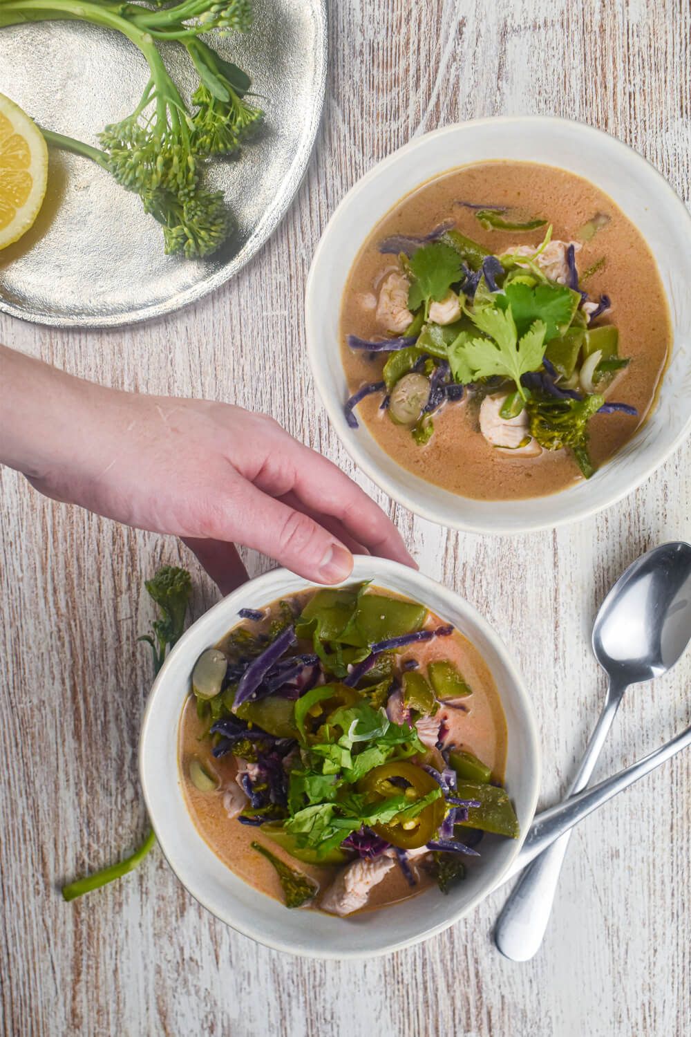 Curry soup with coconut, Thai red curry, vegetables, and chicken breast in two bowls.