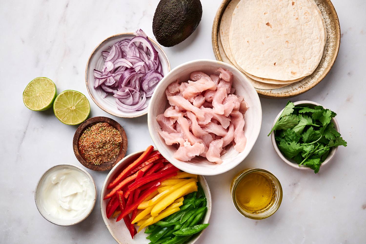 Ingredients for chicken fajitas including chicken fajitas, bell peppers, onions, cilantro, fajita seasoning, tortillas, and avocado.