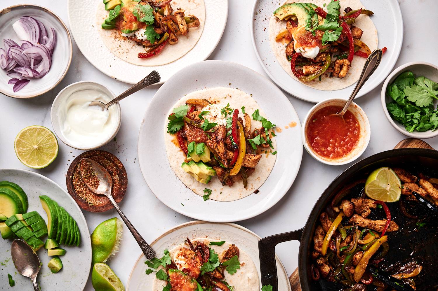 Homemade chicken fajitas served on flour tortillas with sour cream, salsa, cilantro, and avocado.