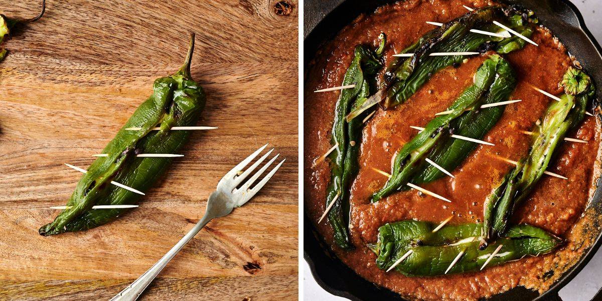 A roasted poblano pepper, pierced with toothpicks to hold its shape, rests on a wooden surface beside a fork. The roasted poblano peppers are nestled in a skillet with a rich, red sauce, prepared for further cooking.