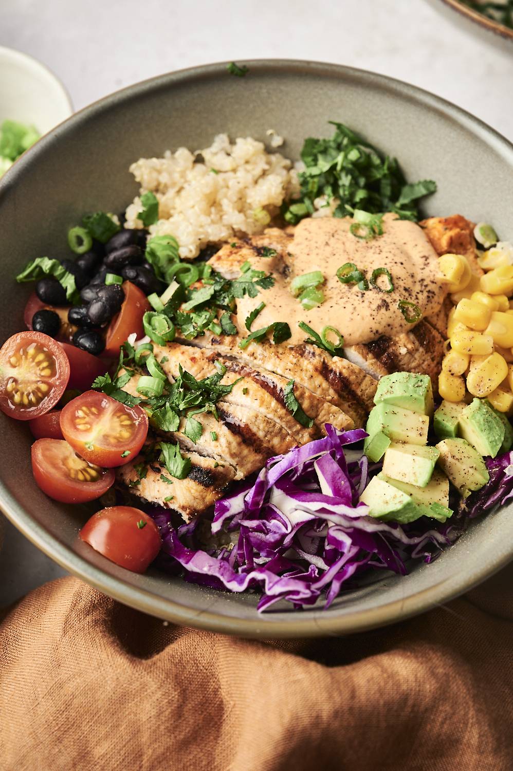 Grilled chicken with quinoa, black beans, corn, grape tomatoes, avocado, red cabbage, and a drizzle of chipotle ranch, topped with green onions and cilantro.