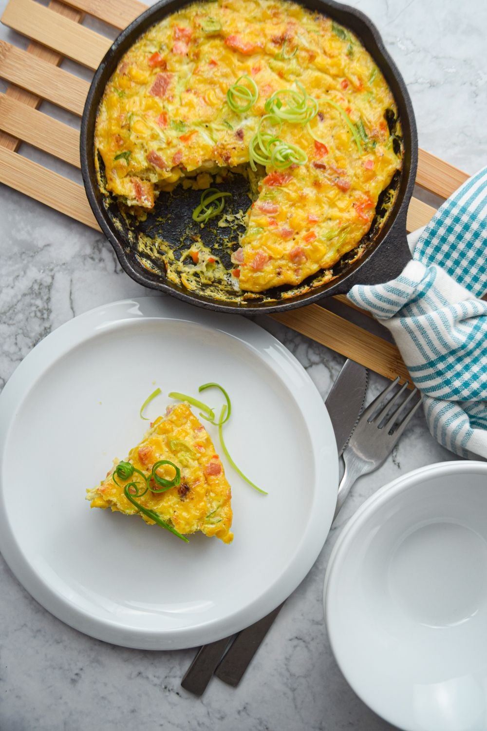 Corn and bacon frittata in a cast iron skillet with peppers, onions, and cheese.