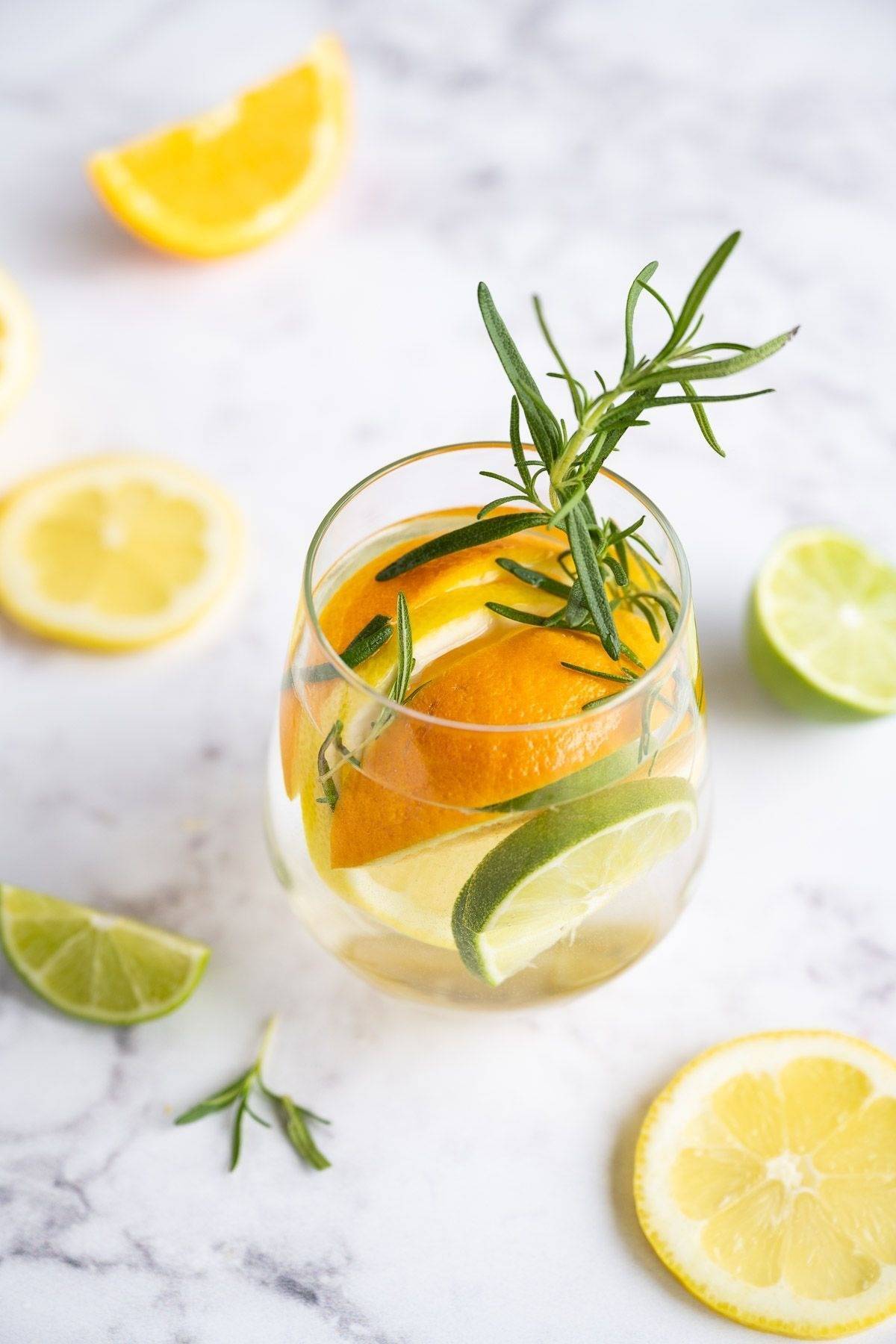 Lemon detox water in a glass with lemon slices, orange slices, and lime slices.