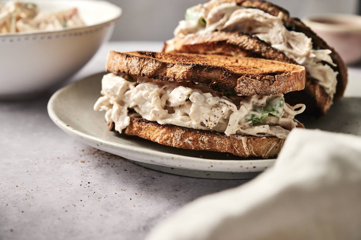 A toasted sandwich filled with creamy chicken salad, served on a rustic plate.