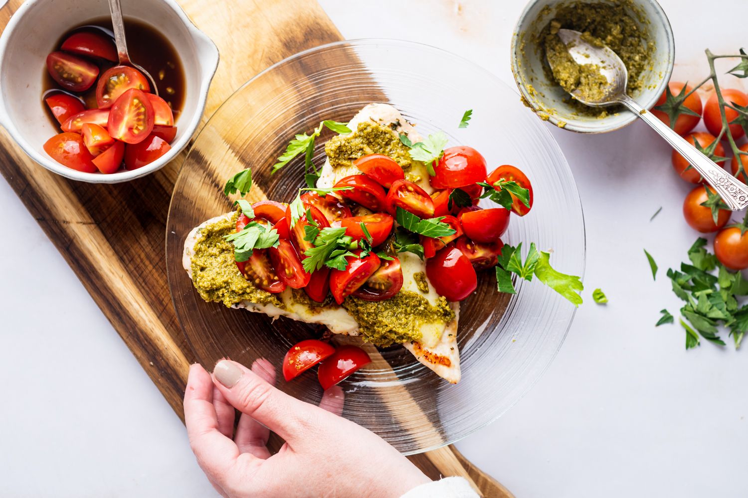 Margherita chicken with grilled chicken breast served with pesto, melted cheese, and tomato salad on a plate.