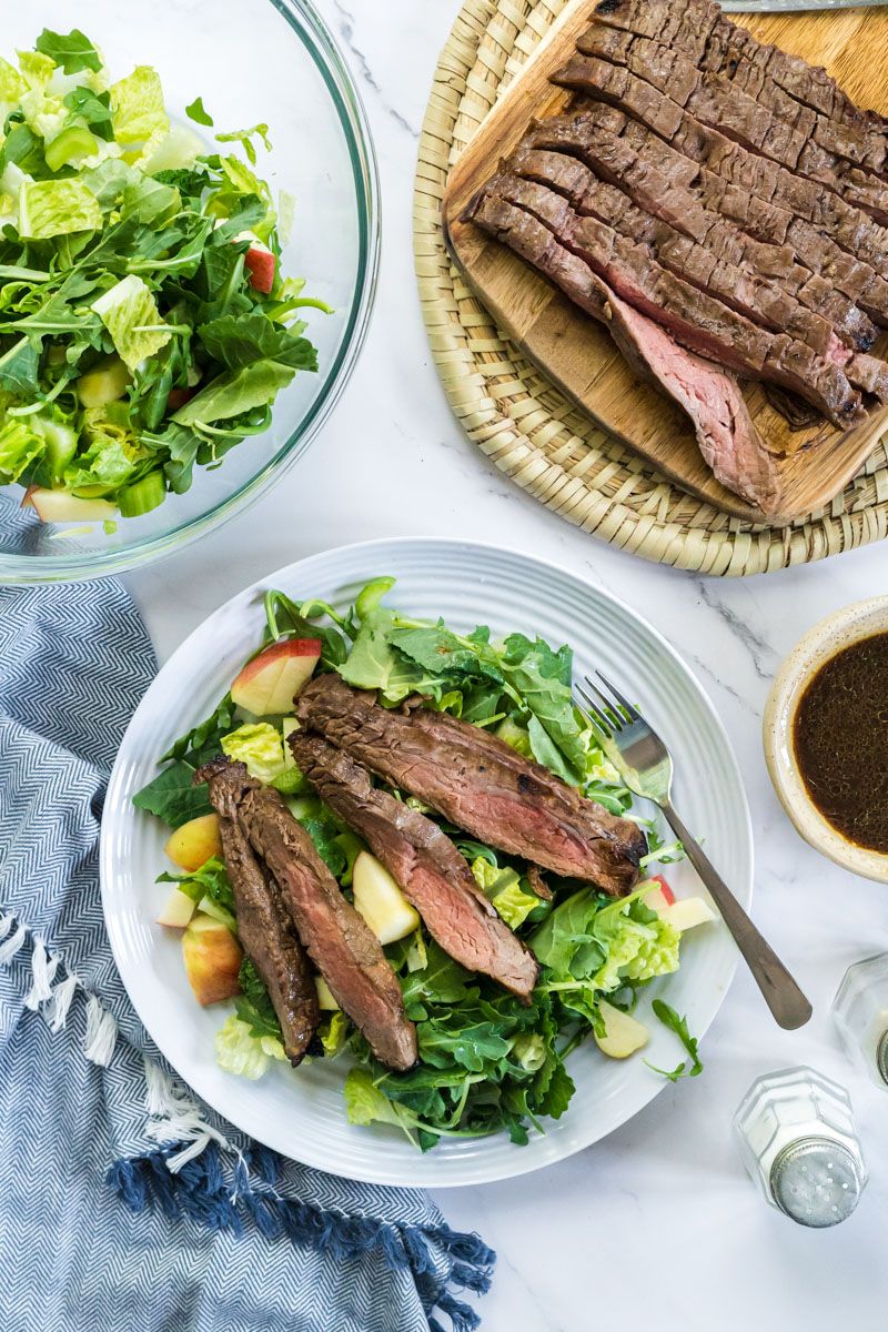 Sliced grilled flank steak served over greens with balsamic marinade on the side.