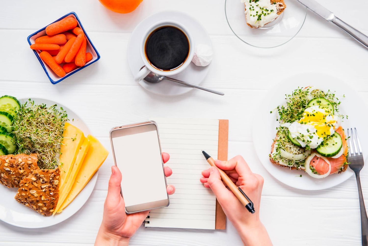 Person writing on notebook with a plate with toast on the side and a coffee cup.
