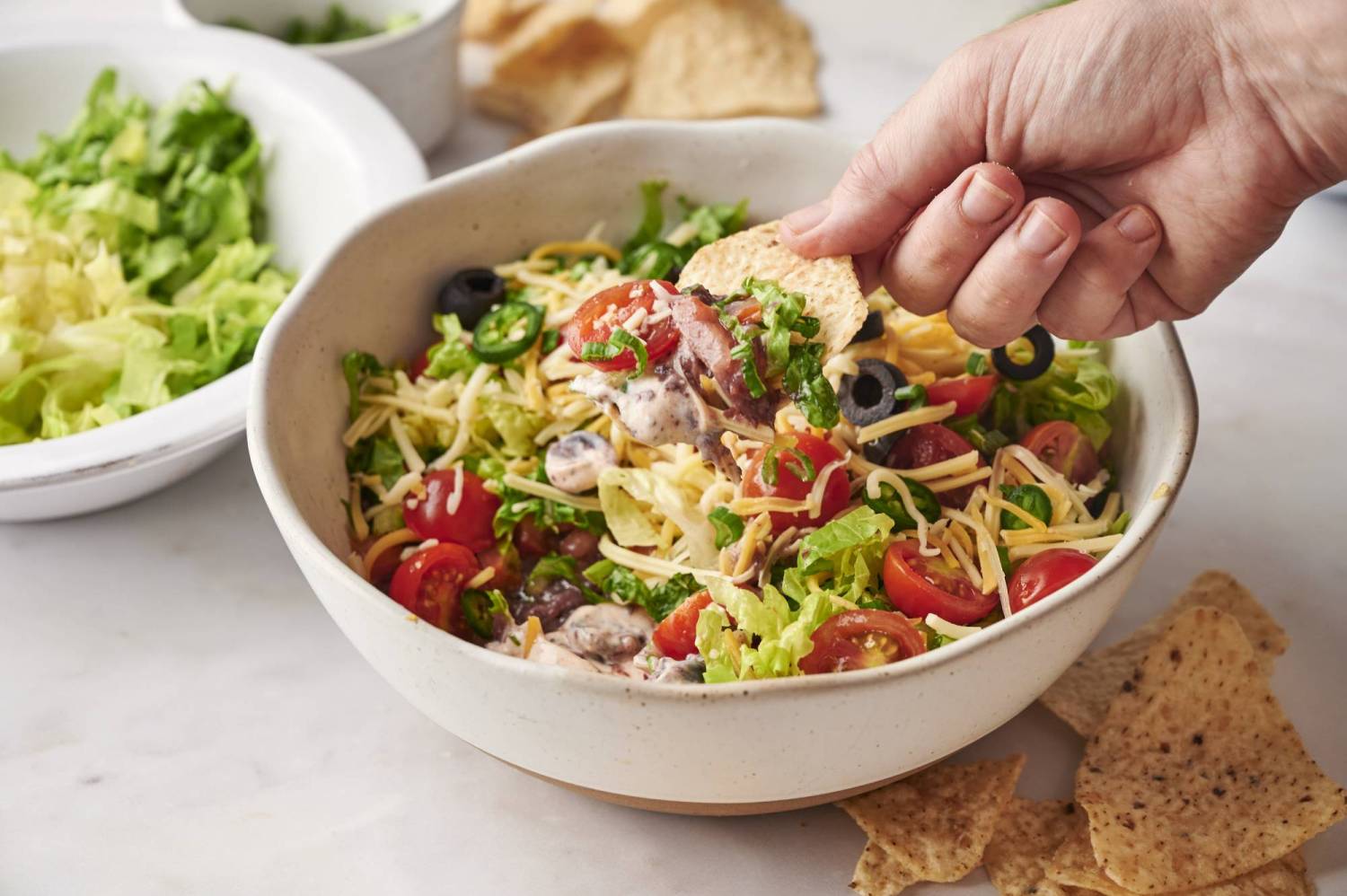 Healthier taco dip being scooped on a tortilla chip.