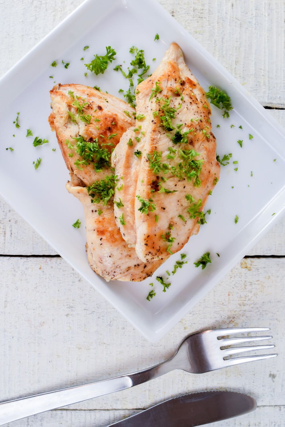 Herb chicken breast with a browned crispy exterior and minced parsley on top.
