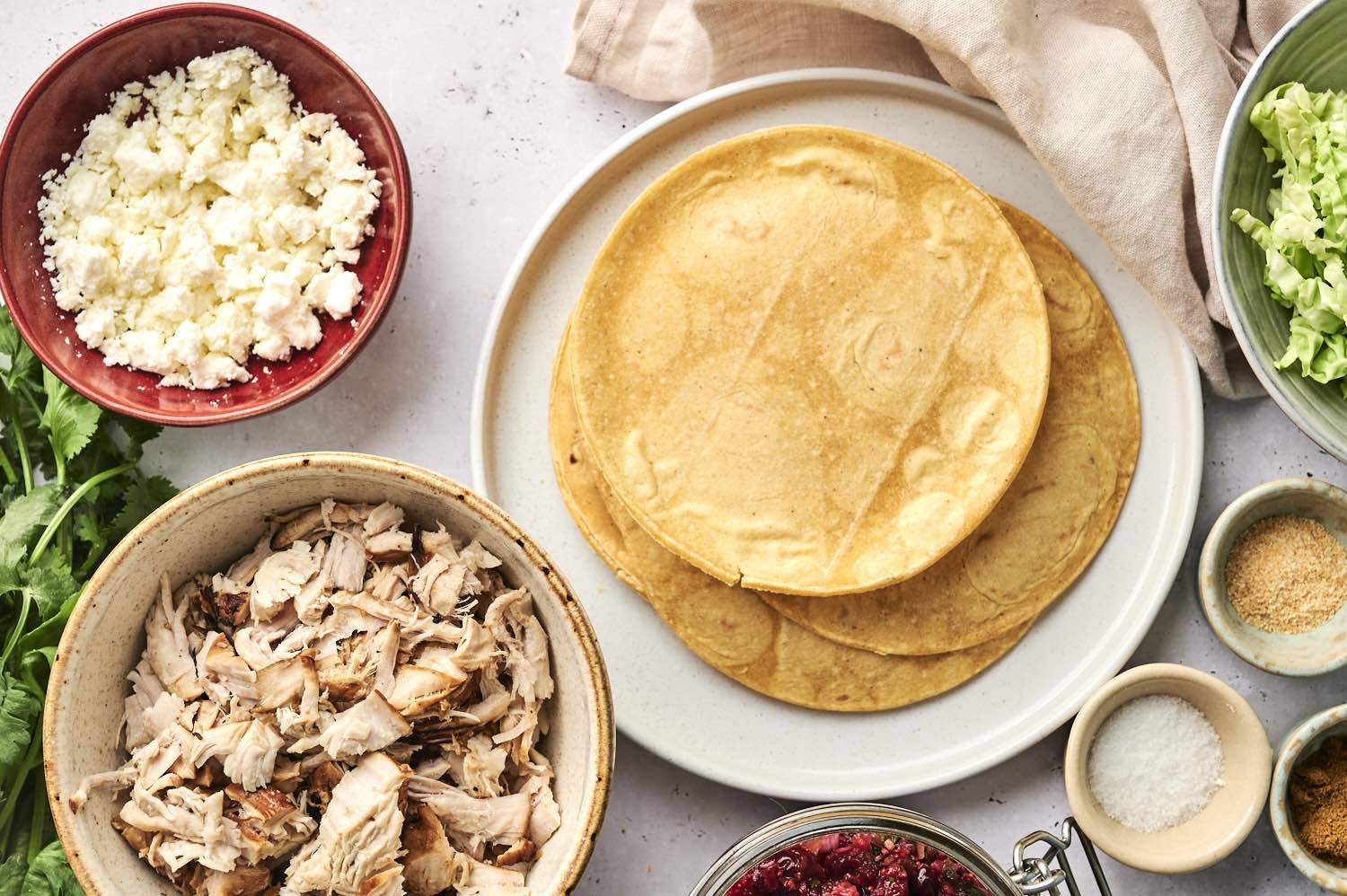 Ingredients for turkey tacos, including cheese, relish, turkey and veggies sitting on the counter.