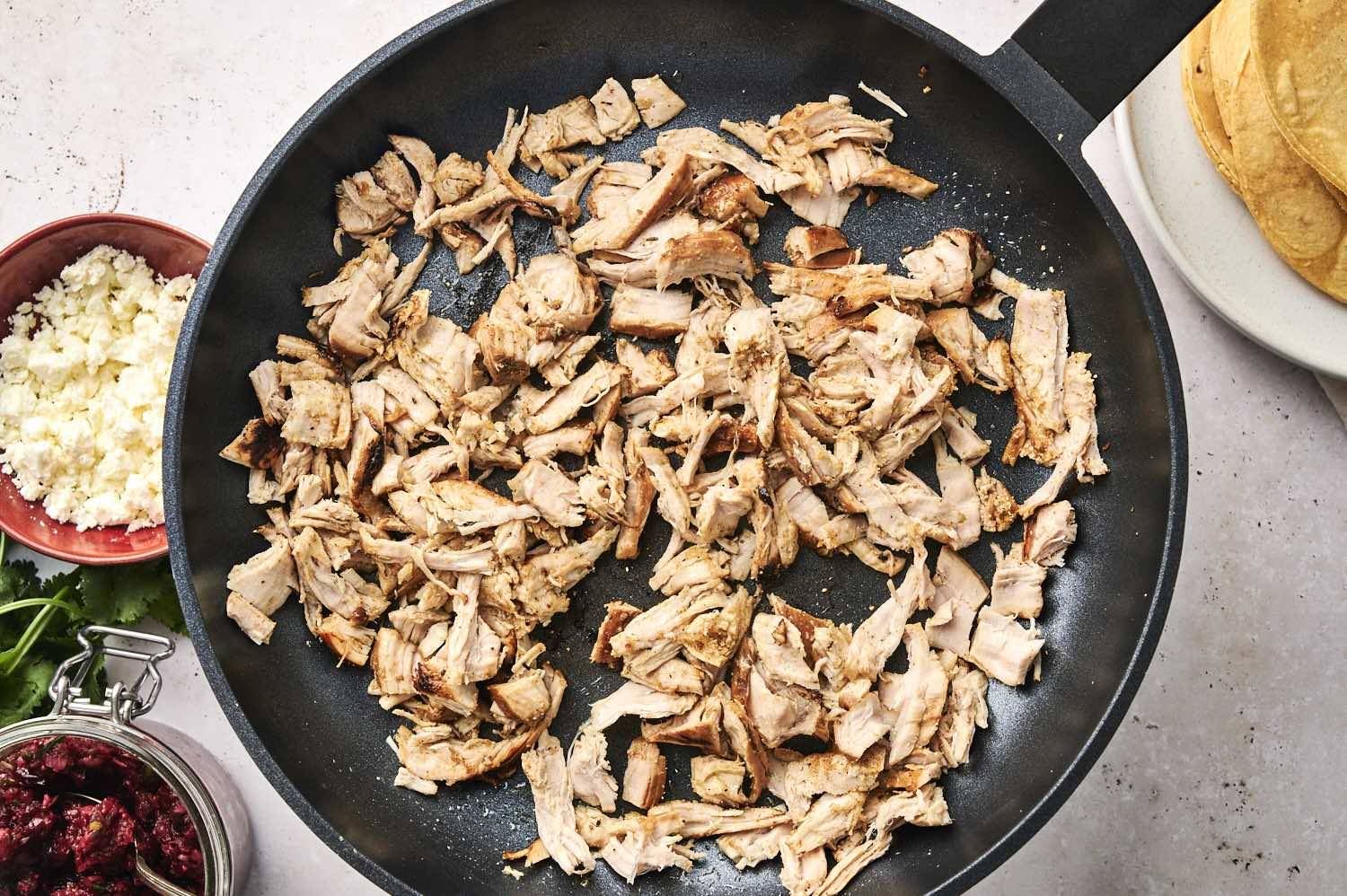Shredded turkey being warmed in a pan on the stove.
