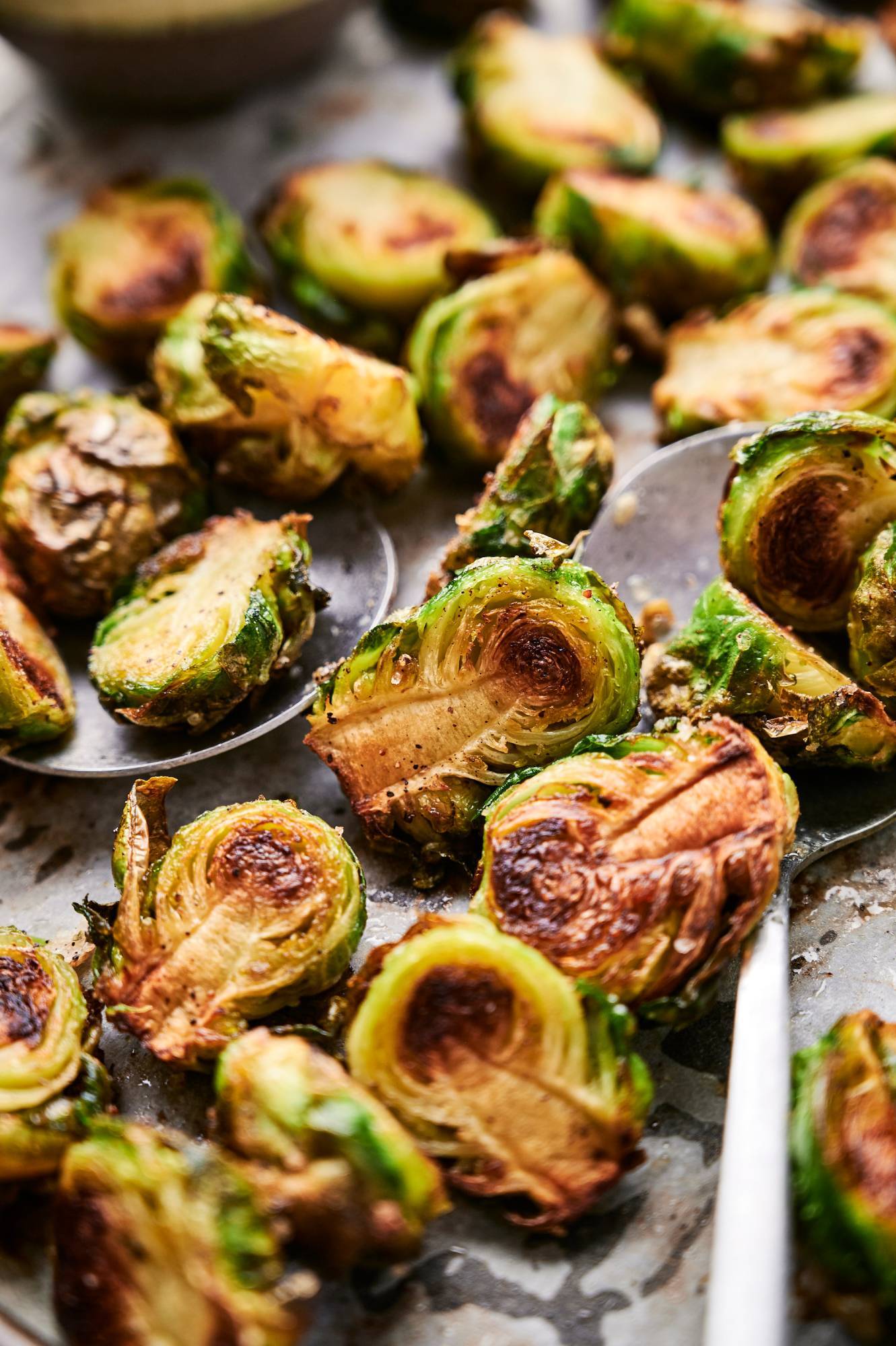 Close up of roasted brussel sprouts on a spoon with crisp, browned edges.