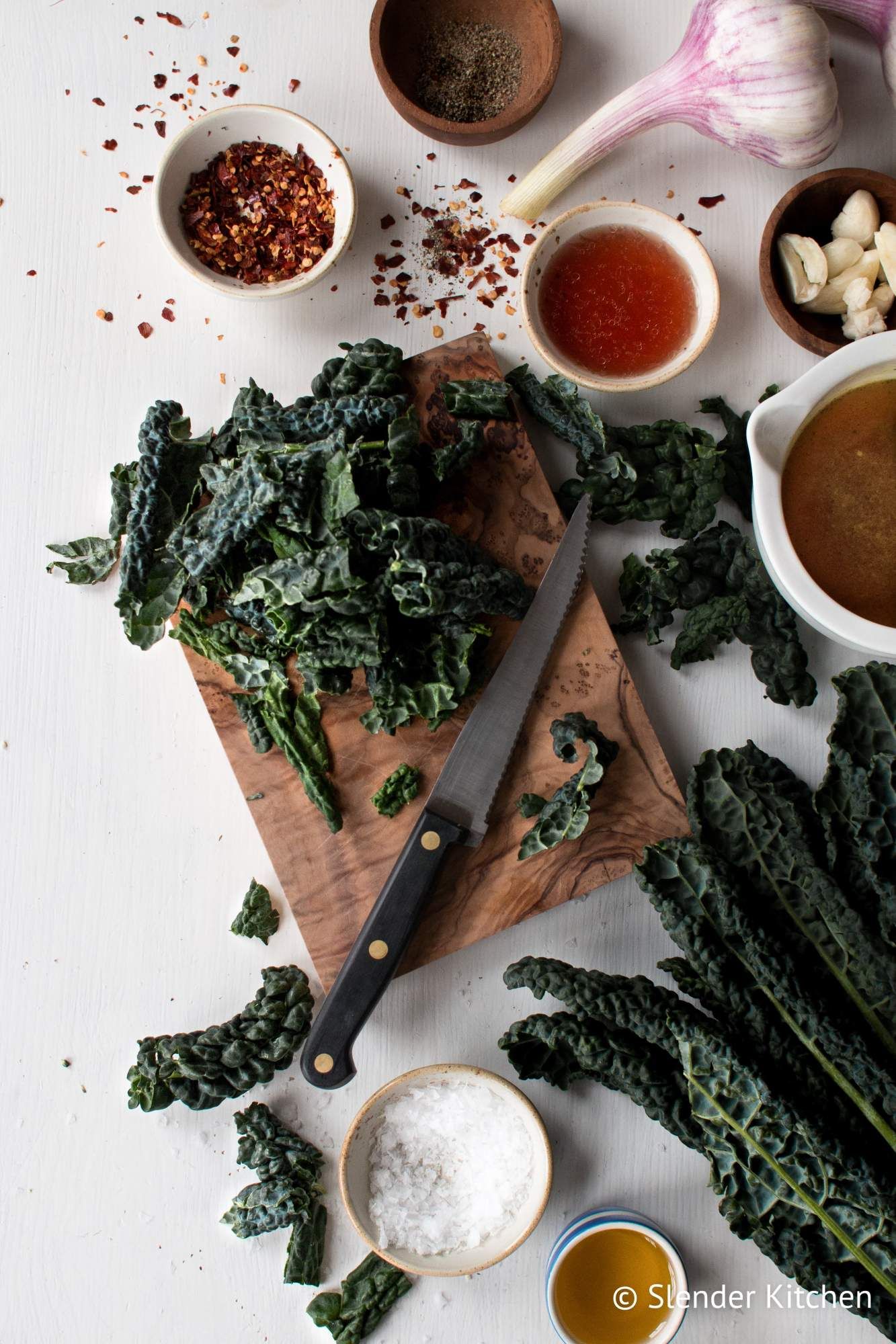 Ingredients for sauteed kale including Lacinato kale, red pepper flakes, garlic, red wine vinegar, and olive oi.