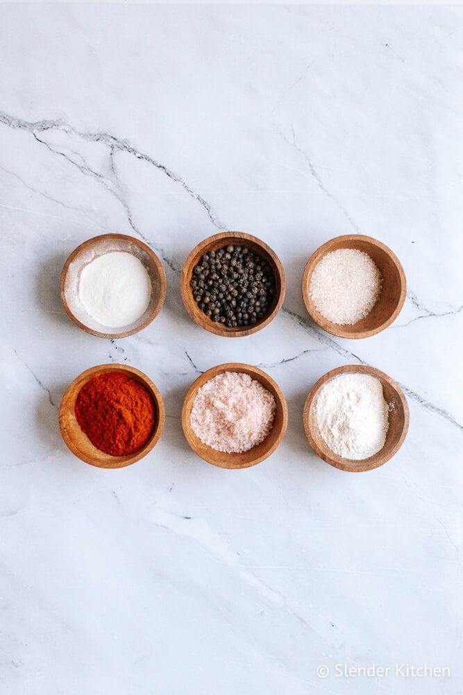 Ingredients for seasoned salt in small bowls including paprika, salt, onion powder, garlic powder, black pepper, and sugar.