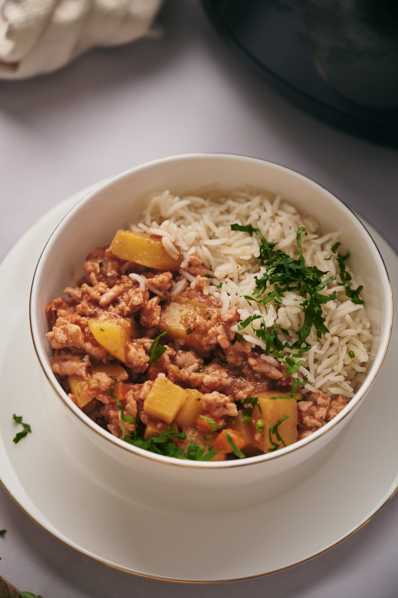 Crockpot picadillo with ground meat, potatoes, cilantro, and white rice in a bowl.
