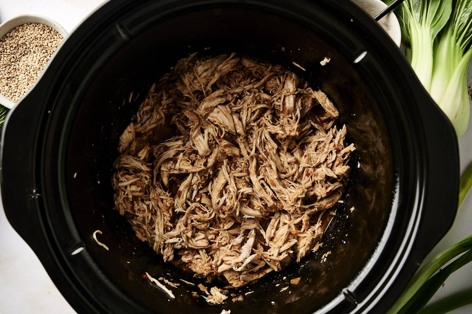 Crockpot with shredded sesame chicken in a sweet and savory sauce.