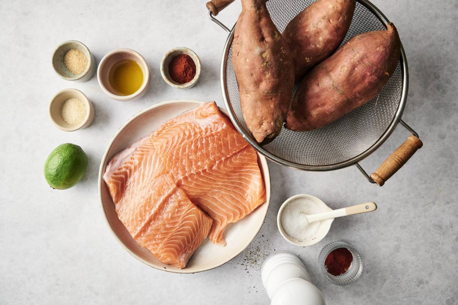 Fresh salmon fillets, sweet potatoes, and seasonings arranged on a countertop for a Southwest-inspired dish.