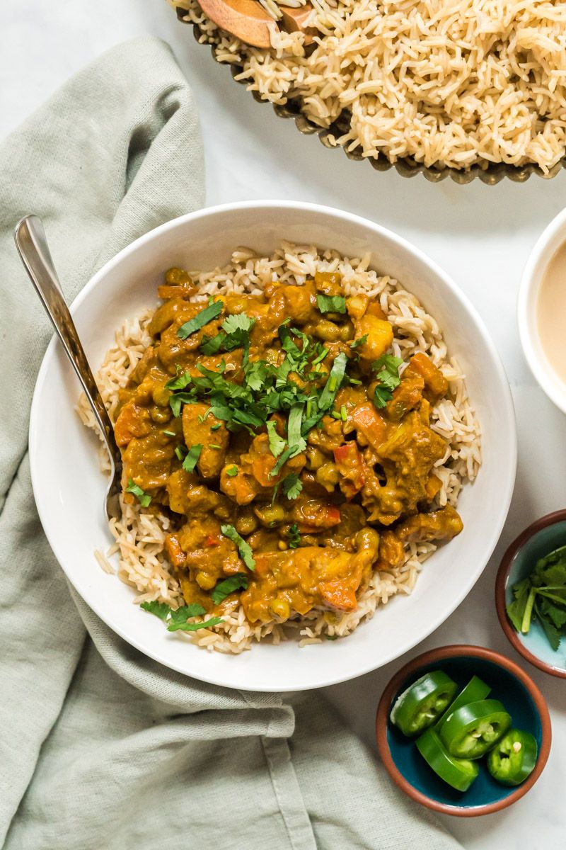 Slow cooker Indian vegetable korma on a plate with brown rice, korma, and fresh cilantro.