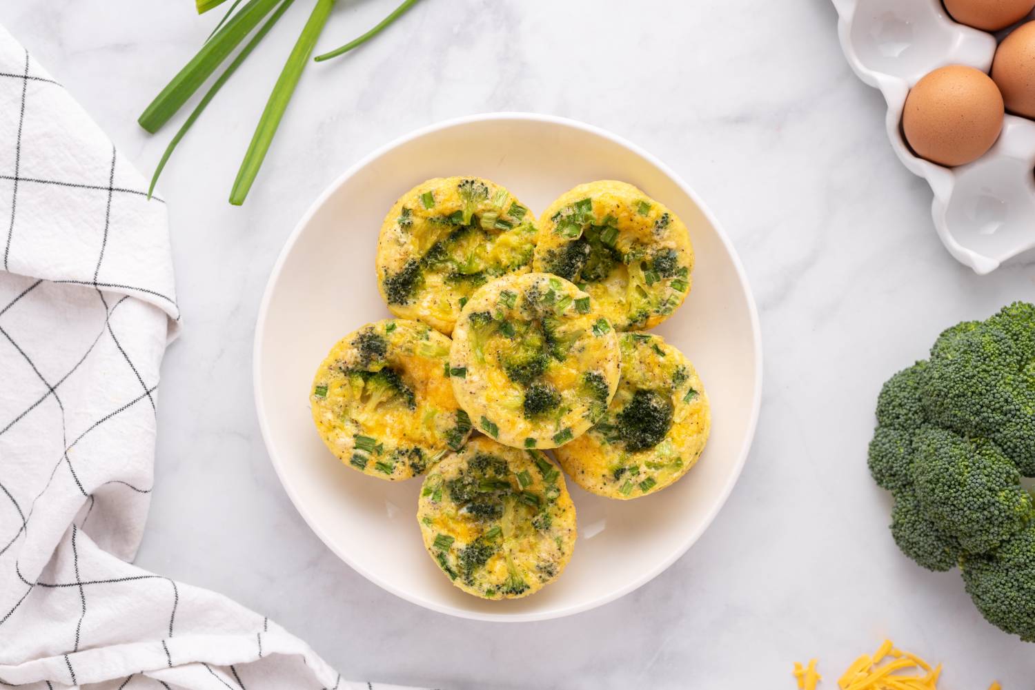 Broccoli cheddar egg muffins in a muffin tin with coffee on the side.