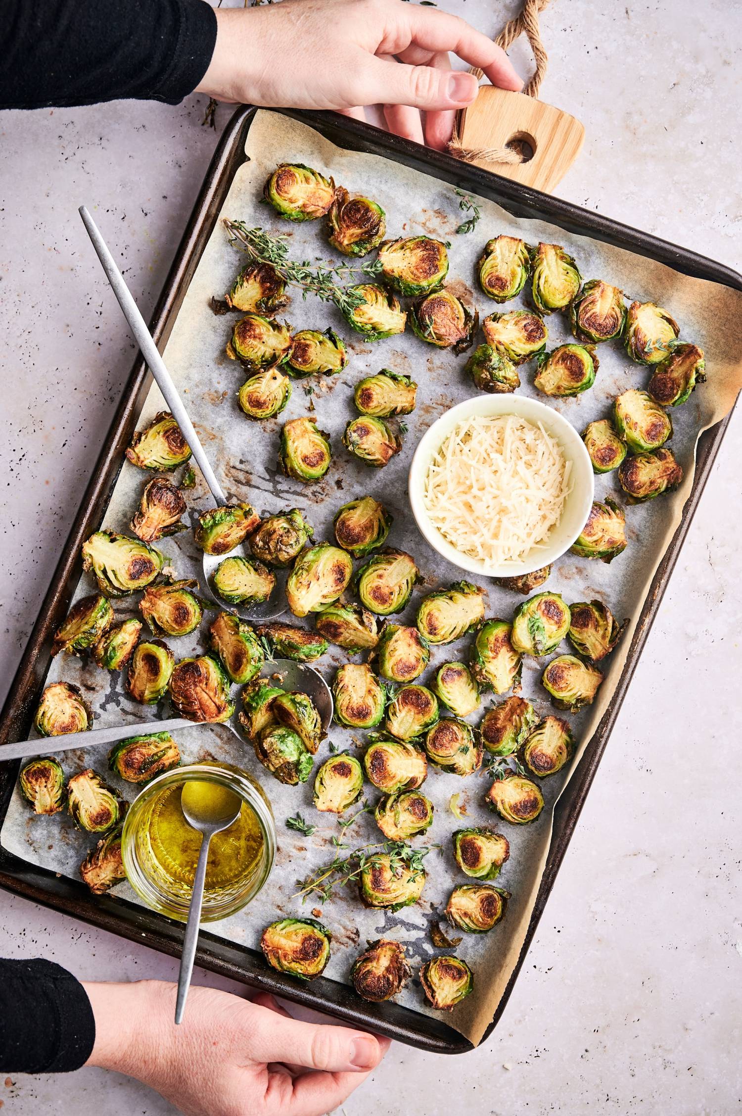Sheet pan with crispy Brussels sprouts served with Parmesan cheese and olive oil.