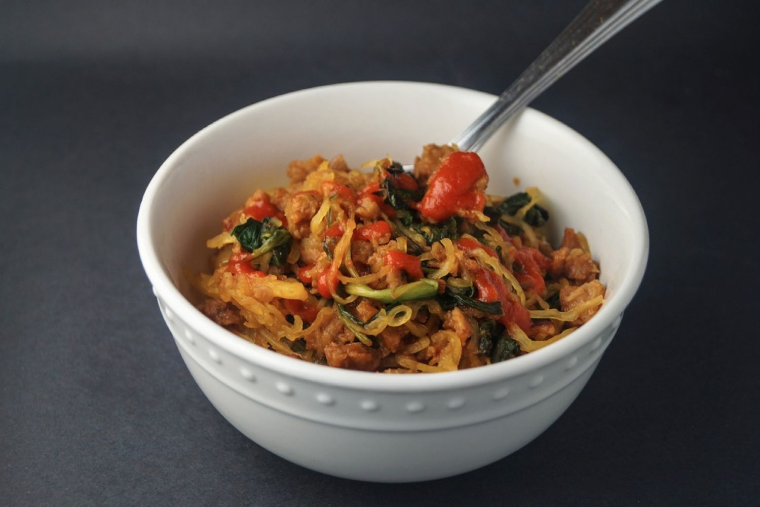Asian spaghetti squash with crumbled sausage, spinach, spicy sauce, and cooked spaghetti squash noodles.