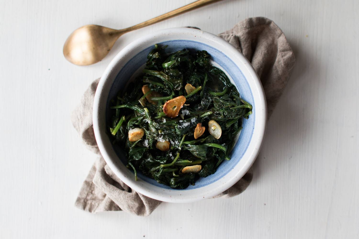 Sauteed spinach with golden brown garlic in a skillet. 