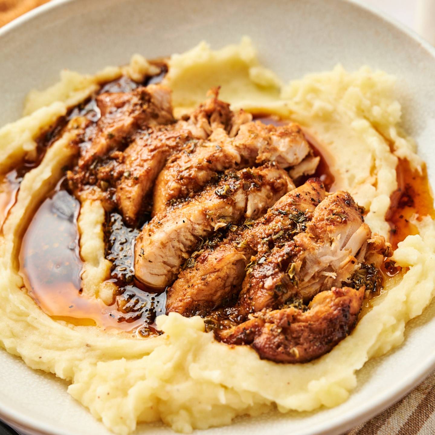 Air fryer turkey breast tenderloin with herbs and sauce on a plate with mashed potatoes.