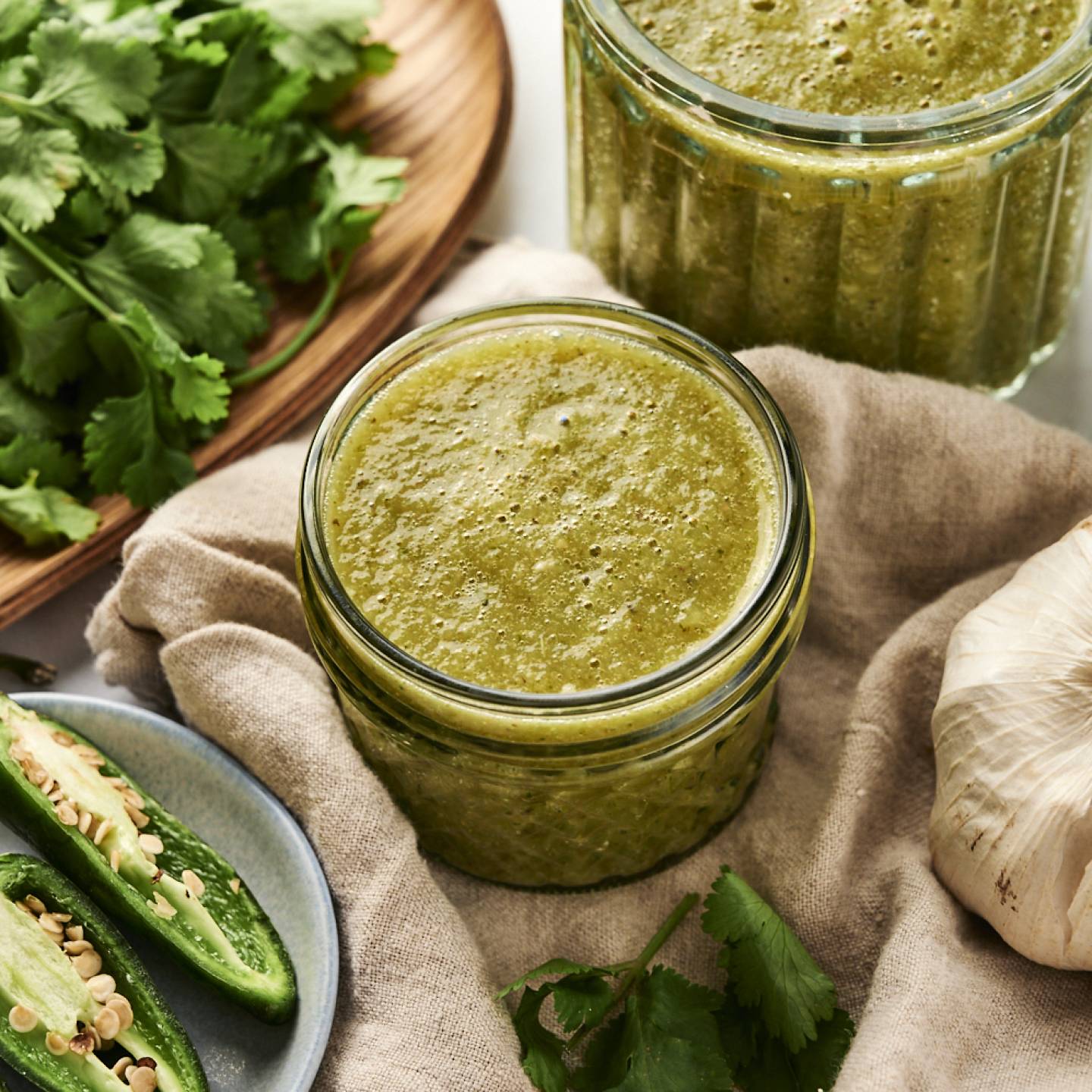 Green enchilada sauce with tomatillos and jalapenos stored in a glass jar.