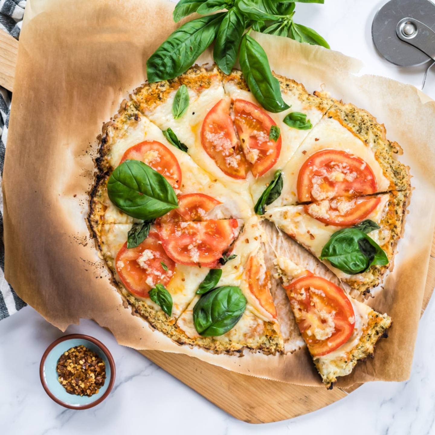 Cauliflower crust pizza made with cauliflower florets and topped with mozzarella cheese, tomatoes, and basil for a low carb pizza.