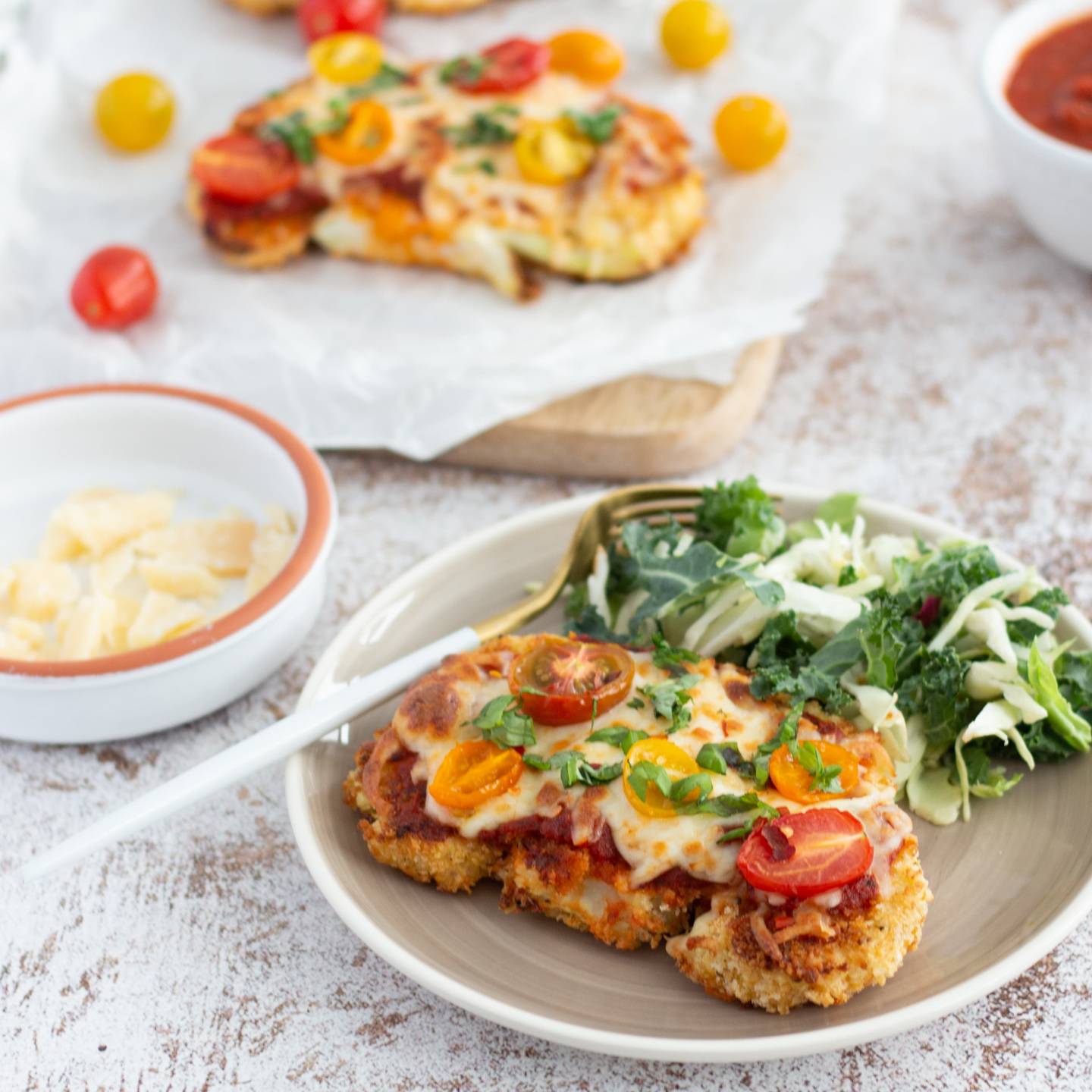 Cauliflower parmesan with breaded cauliflower steaks topped with marinara sauce, melted cheese, and cherry tomatoes.