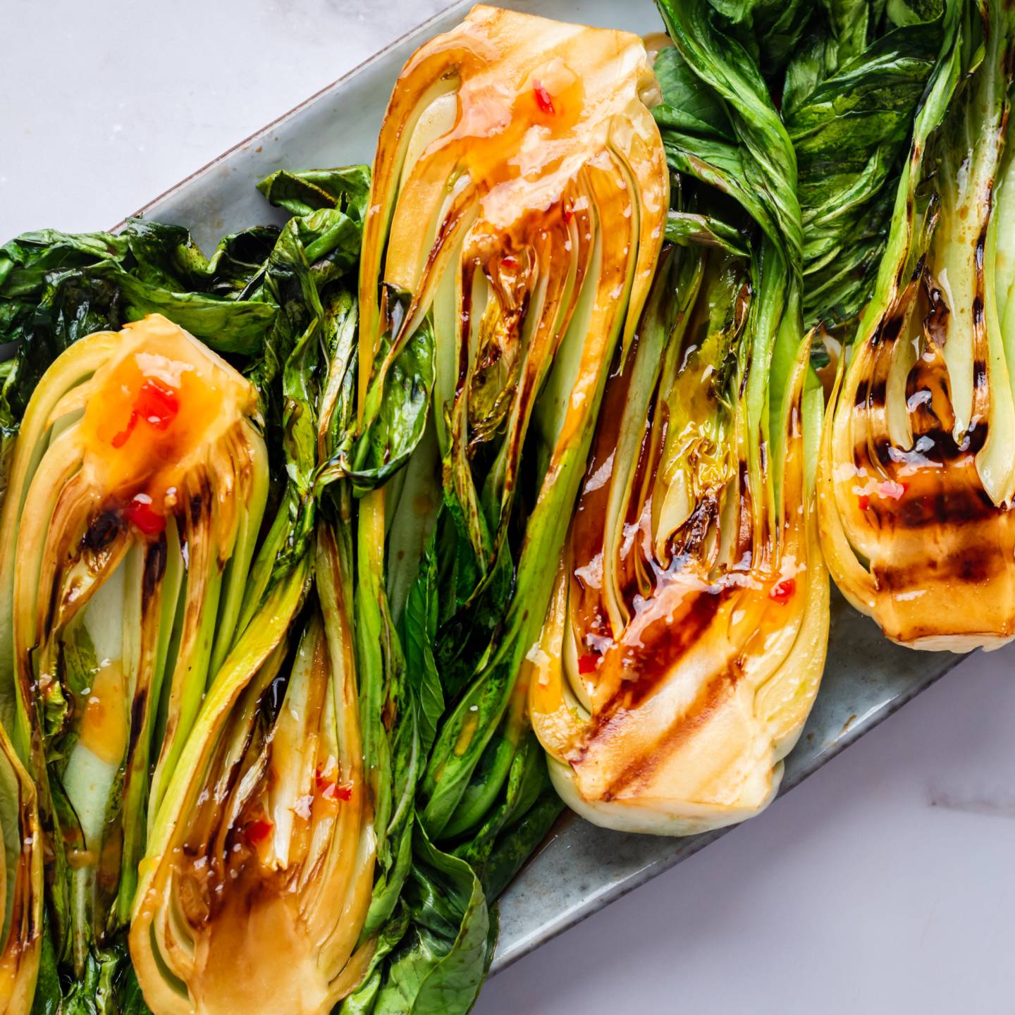 Grilled bok choy with sweet chili sauce served on a plate. 