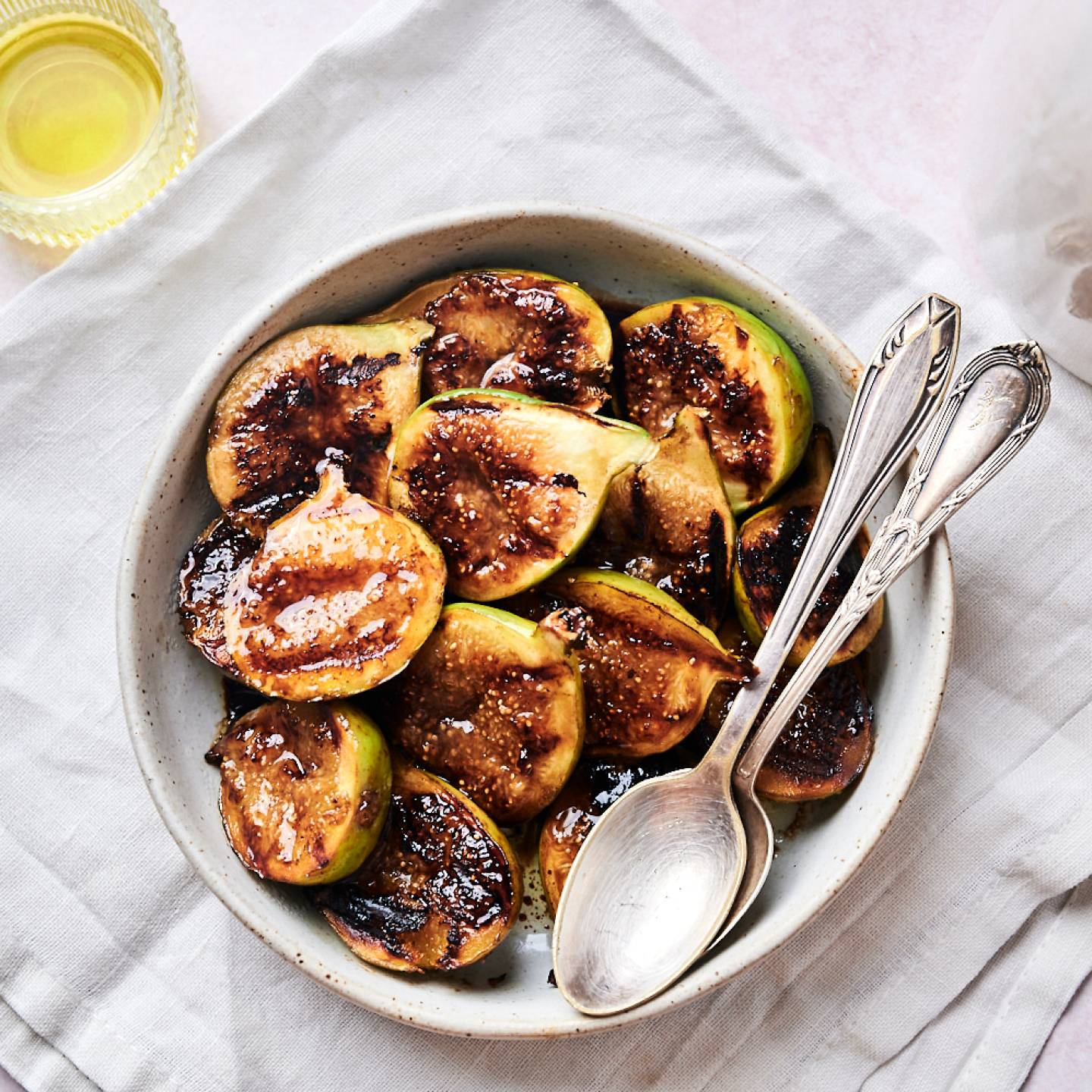 Grilled figs with balsamic glaze served in a bowl with two spoons.