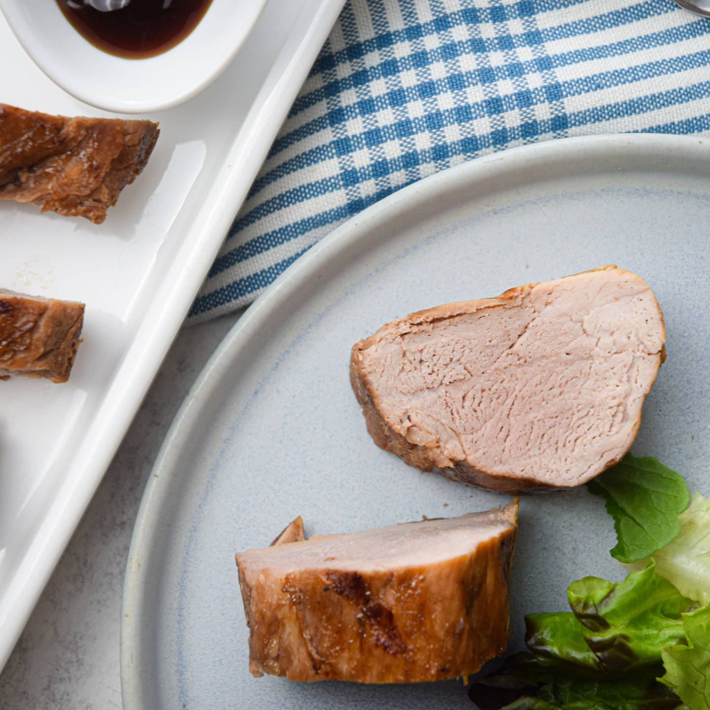 Grilled hoisin pork tenderloin with an Asian marinade on a plate with greens.